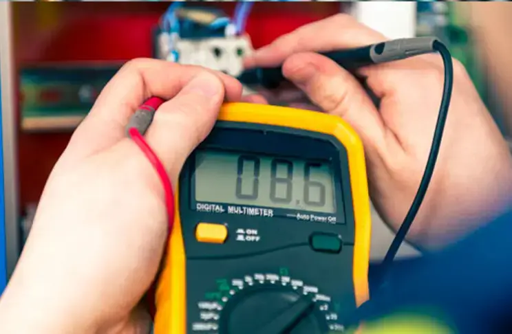 Electrician reading a digital multimeter during EICR